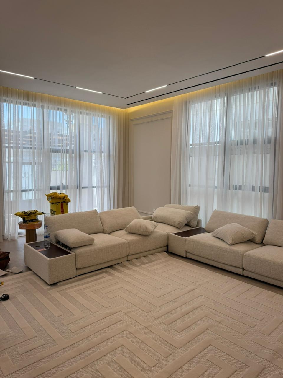 Floor-to-ceiling soft architectural sheer drapery filtering natural light across a modern living room space